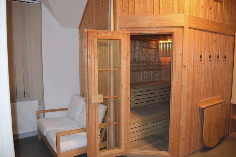 Sauna s otvorenými presklenými dverami a osvetlenými lavicami.